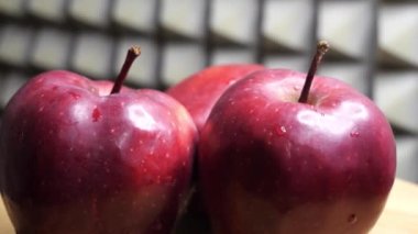 Three wet apples of the red chief variety on a rotating surface. Ripe fruits.