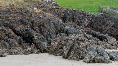 Open rocks on sandy soil. Green grass.