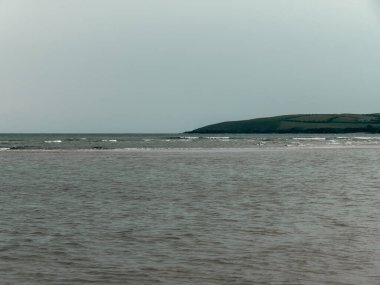 Cold sea on a cloudy day. A hill on the seashore. Seascape. Ocean waves