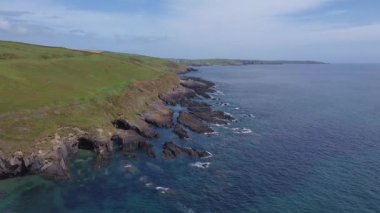 Picturesque green hills on the coast. Rocky coast of the Atlantic Ocean on a sunny day. The blue water of the Celtic Sea.