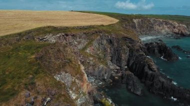 Farm fields on the coast. Landscape of the West Cork. Picturesque rocks on a sunny day. The area near Clonakilty.