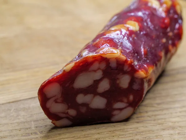 Dried sausage on a cutting board, food close-up shot. Sausage with a lot of fat.