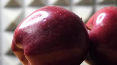Two apples of the red chief variety rotate in the frame. Big red apples close-up. Macro video, soft focus.