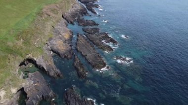 Kelt Denizi kıyısındaki siyah kayalar. Güzel deniz manzarası. Güney İrlanda 'nın sahil bölgesi County Cork' ta. Atlantik 'in mavi suları, tam HD formatında havadan görüntüler..