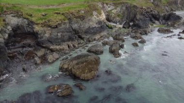 İrlanda, County Cork 'taki güzel Atlantik Okyanusu kıyısı. Deniz dalgaları kıyıdaki kayalara vurur, beyaz deniz köpüğü.