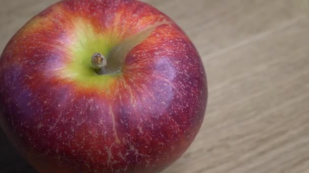 1つの大きな赤いリンゴは 木製の表面 クローズアップビデオで回転します 4Kビデオでアップルとテキストのための場所 — ストック動画