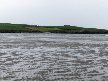 Deniz kıyısındaki dalgalı kumlar. Bulutlu bir günde deniz manzarası. Suya yakın kumda güzel desenler var..