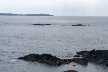 Atlantik Okyanusu 'nun suları arasındaki kayalar. Deniz Burnu. Kuzey Avrupa 'da, İrlanda' da soğuk bahar. Bulutlu havada Kelt Denizi. Deniz manzarası. Gökyüzünün altında mavi deniz