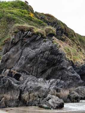 Çimlerle kaplı taş bir tepe. Saf kaya. Manzara. Bulutlu gökyüzünün altındaki kayalık dağda yeşil çimenler
