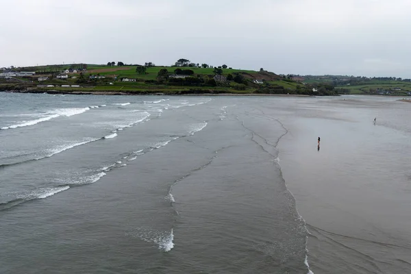 Tidal waves on Inchydoney Beach on a cloudy day. A few vacationers on the beach in the south of Ireland. Seaside landscape. The famous beach near the town of Clonakilty. Picturesque places of Ireland.