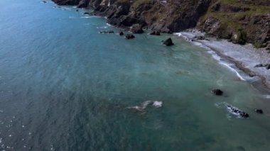 Kıyıdaki sarp kayalıklar. Güzel deniz manzarası. Helikopterden alınan video tam HD formatında. Kıyı dalgaları, sörf.