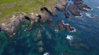 Kıyıdaki siyah kayalar. Güzel deniz manzarası. Güney İrlanda 'nın sahil bölgesi County Cork' ta. Atlantik 'in mavi suları, tam HD formatında havadan görüntüler..