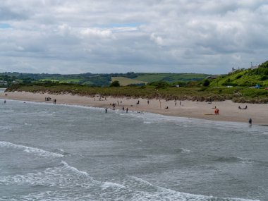 West Cork, İrlanda, 12 Haziran 2022. Inchydoney sahilinde birçok insan, bulutlu bir gün. Meşhur İrlanda plajı. Popüler bir İrlanda tatil köyü.