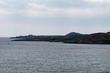 Glandore sahilindeki kasvetli tepeler. Deniz üzerinde bulutlu bir gökyüzü. Deniz Burnu. İrlanda 'nın Doğası.