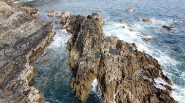 Atlantik Okyanusu 'nun güzel sahil kayalıkları. Deniz dalgalarında beyaz köpük. Deniz dalgaları arasında kayalar.