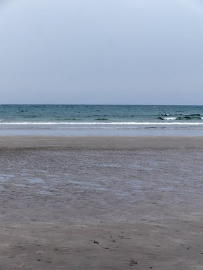 Kelt Denizi kıyısı. Serin bir günde ıslak kumlu plaj. Minimalist deniz manzarası. Bulutlu serin hava.