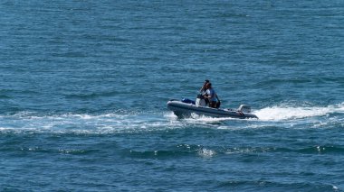 County Cork, İrlanda, 28 Mayıs 2022. Güneşli bir bahar gününde, mavi bir denizde, motorlu bir teknede iki adam yelken açıyor..