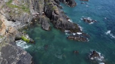 Kıyıdaki siyah kayalar. Güzel deniz manzarası. County Cork 'taki İrlanda' nın sahil bölgesi. Atlantik 'in mavi suları, tam HD formatında havadan görüntüler..