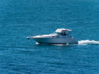 County Cork, İrlanda, 28 Mayıs 2022. Güneşli bir günde, yüksek hızlı bir tekne denizde yelken açar. Su yüzeyinde bir tekne, deniz manzarası. Denizde beyaz motorlu tekne