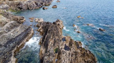 Güzel uçurumlar. Deniz dalgalarında beyaz köpük. Deniz dalgaları arasında kayalar.