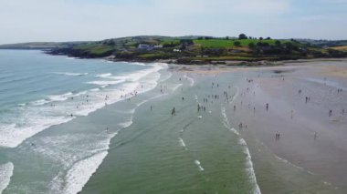 Çoğu insan boş zamanlarını İrlanda 'nın Inchydoney plajında geçirir. Yazın güzel İrlanda kıyıları, İHA videosu. Deniz manzarası ve kumsal..