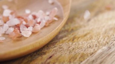 Himalaya 'nın sert kristalleri kırsal bir masada ahşap bir kaşığa tuz döküyor. Ağır çekim. Makro çekim