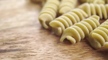 Fusilli İtalyan pişmemiş makarna. Mutfak tahtasında yeşil bezelyeli makarna. Makro. Dolly vurdu. Akdeniz mutfağı kavramı