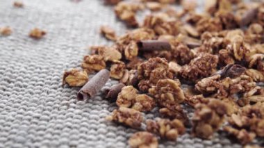 Çikolatalı granola ve buğday tohumu. Kahverengi doğal yulaf müsli gri çuval bezi jüt paspasın üzerinde. Sağlıklı çiğ yulaf ezmesi konsepti. Dolly vurdu..