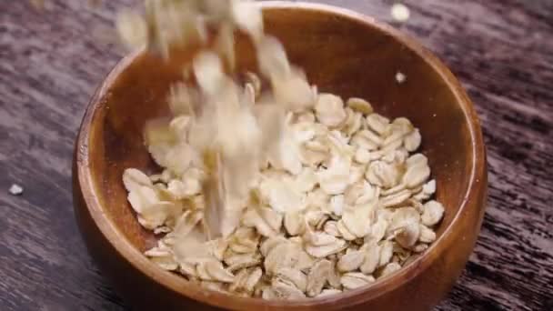 Uncooked Dry Rolled Oatmeal Falls Slow Motion Rustic Wooden Bowl — Stock Video