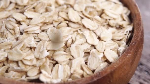 未煮熟的干燕麦片慢吞吞地掉进木桌上一个生硬的木制碗里 有机燕麦食品概念 — 图库视频影像