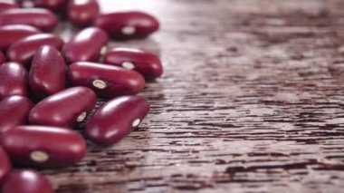Kırsal kahverengi ahşap bir yüzeyde pişmemiş kırmızı böbrek fasulyesi. Makro. Çiğ organik baklagiller. Dolly vurdu.