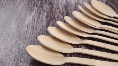 Kırsal ahşap bir yüzey üzerinde tahta bambu kaşıklar. Tek kullanımlık piknik seti. Mutfak ekolojik aletleri. Geri dönüşüm konsepti. Kapatın. Dolly vurdu.