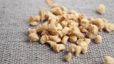 Organik kurutulmuş soya fasulyesi parçaları sert bir jüt yüzeyine yakın çekimde düşer. Sebzeli soya kahvaltısı.