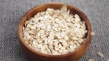 Kuru yulaf ezmesi ağır çekimde kaba bir jüt çuval bezinin üzerine dökülür. Fırında pişmemiş yulaf. Sağlıklı kahvaltı konsepti. Kapatın. Döndürme