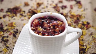 Bir kaşık dolusu çiçekli meyve çayının içine dökülen bir kaşık kırsal jüt çuval bezi. Kapat.