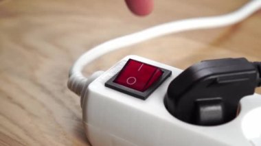 Fişe bağlı olan güç bağlantısının kırmızı düğmesini açıyorum. Kapatın. Elektrik ve yeşil enerji kavramı. Eko ahşap bir yüzeyde