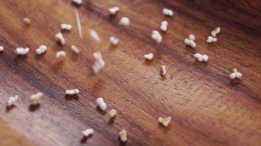 Amaranth patladı, kuru taneleri şişirip yavaş çekimde kırsal bir ahşap yüzeye düştü. Pseudocereal yiyecek, glütensiz. Makro