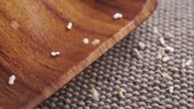 Patlamış kehribar taneleri. Kırsal bir çuval bezi yüzeyine düşmek ve ağır çekimde ahşap mutfak gereçleri. Kuru amaranthus gevreği. Makro. Süper yiyecek konsepti