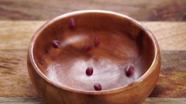 Kırmızı adzuki ya da azuki fasulyesi. Pişmemiş baklagiller ahşap desenli bir yüzeyde kırsal bir ahşap kaseye düşerler. Ağır çekim. Kapatın. Geleneksel Japon yemekleri. Vigna angularis