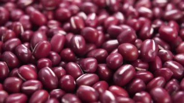 Kırmızı adzuki ya da azuki fasulyesi. Yavaş çekimde pişmemiş organik baklagil taneleri düşüyor. Makro. Geleneksel Japon yemekleri. Döndürme