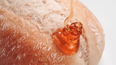 Ağır çekimde taze bir çöreğin kabuğuna bal dökülüyor. Makro çekim