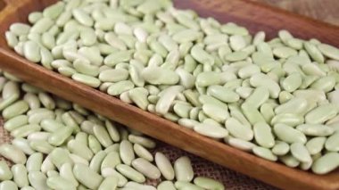 Kuru yeşil Verdina fasulyeleri ahşap kaplara dökülüyor. İspanya, Asturias ve Galiçya 'dan pişmemiş baklagiller. Geleneksel İspanyol mutfağı. Sağlıklı çiğ organik gıda. Yavaş çekim