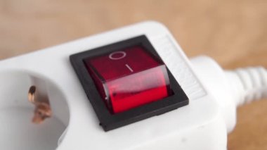 Elektrik konnektöründen elektrik sağlamak için kırmızı düğmeyi açıyorum. Kapatın. Kahverengi arka planda beyaz elektrik şeridi