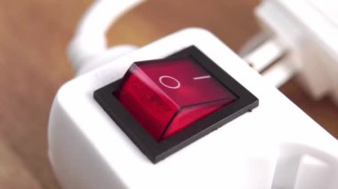 Ev elektriği şeridinin kırmızı düğmesine basarak elektriği kapatmak. Parmağını kapat. Uzatma kablosu. Enerji tasarrufu kavramı. Elektriksel aygıt eklentisi bulanık