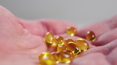 Palmiye içinde sarı Omega 3 kapsülleri. Buruşuk kuru deri. Makro. Doğal destek konsepti. Vücut bakımı fikri