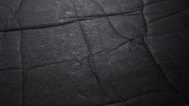 Siyah grunge kıvrılmış katlanmış kağıt dokusu. Makro. Yavaş dönüş. Soyut koyu arkaplan