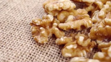 Kaba bir kumaşta çiğ ceviz taneleri. Makro. Yavaş dönüş. Bir yığın taze fındık.