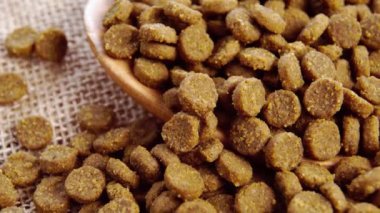 Tahta kaşık dolusu kuru kedi maması. Besleme dokusu. Makro. Yavaş dönüş. Kırsal ve kaba bir çuval bezinde