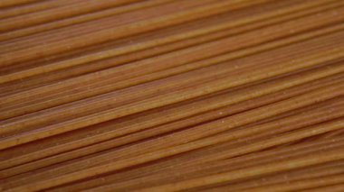 Çiğ buğday soslu spagetti. Makro. Döndürme. Kuru integral gıda. Kahverengi organik makarna