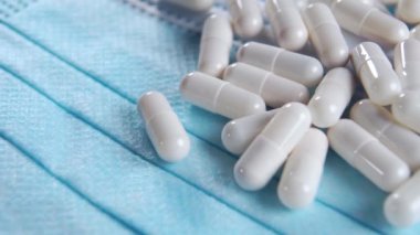 Tıbbi koruyucu maskenin üzerindeki kapsüller yakın plan. Coronavirus omicron tıbbi tedavi ve önleme konsepti. Makro. Döndürme. Beyaz haplar